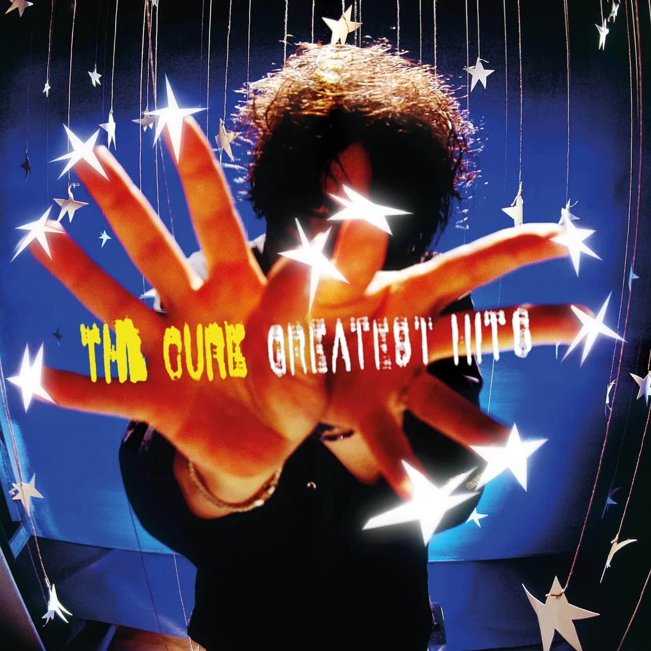 Album cover for 'The Cure Greatest Hits' with a hand and stars
