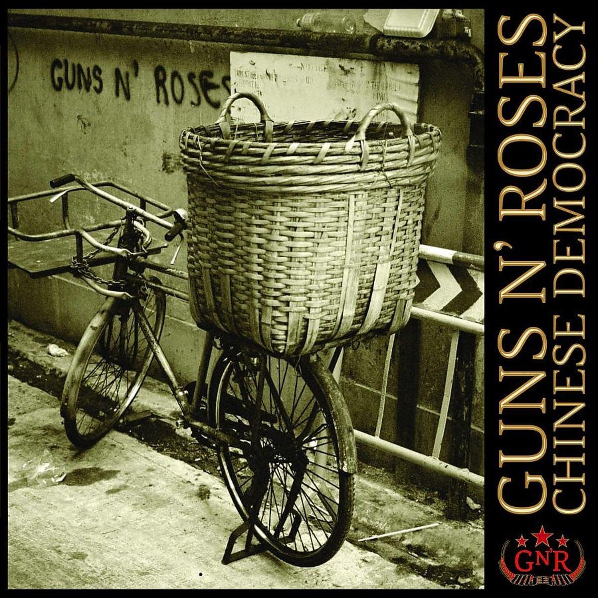 Album cover for Guns N' Roses' 'Chinese Democracy', featuring a sepia-toned photograph of a bicycle with a large woven basket on a sidewalk against a wall with graffiti.