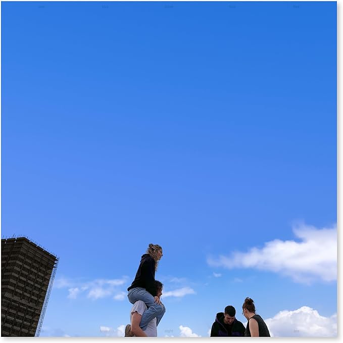 Three people standing on a ledge with a clear blue sky and a building in the background