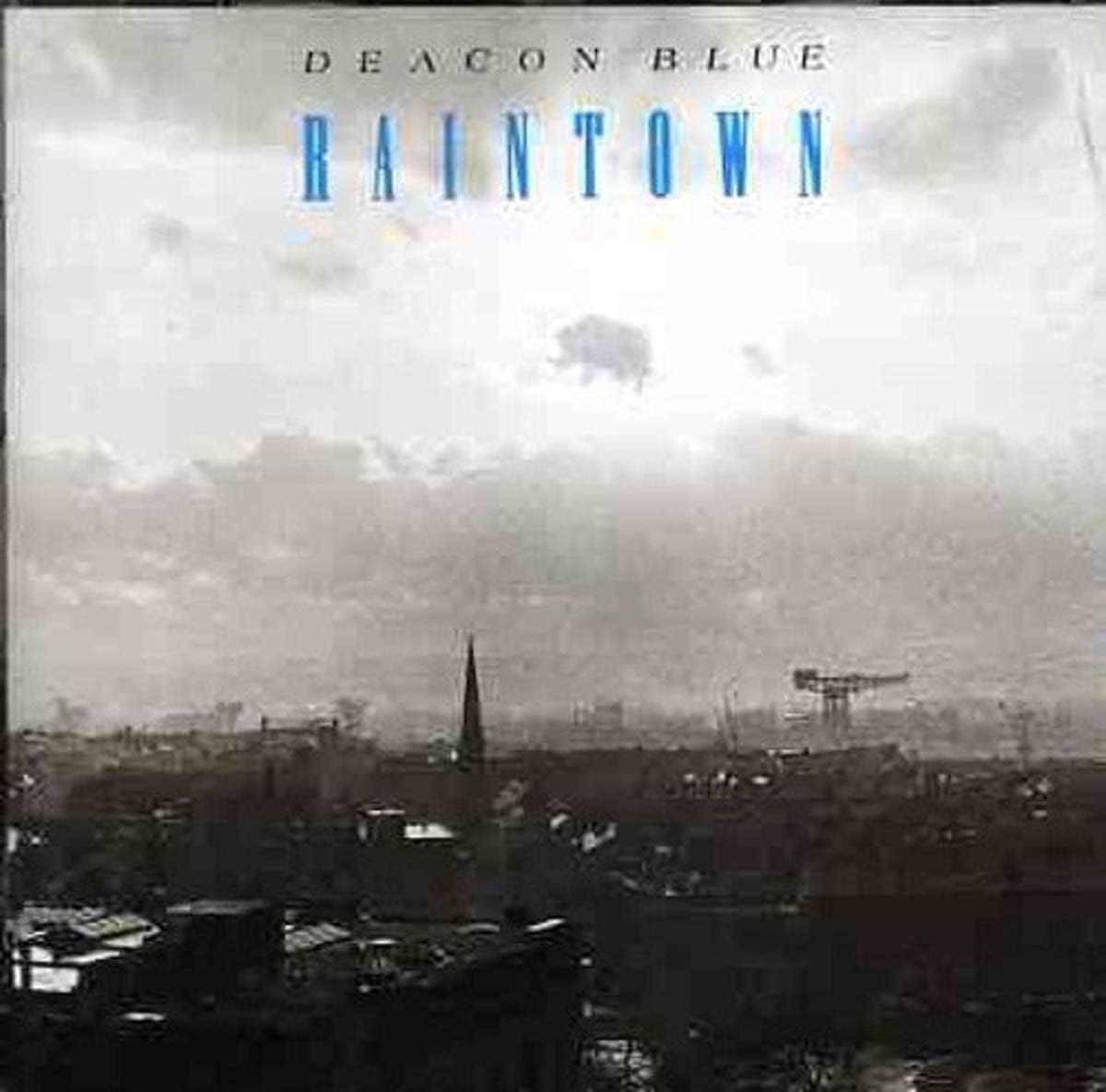 Album cover of 'Raintown' by Deacon Blue with a cityscape and cloudy sky.