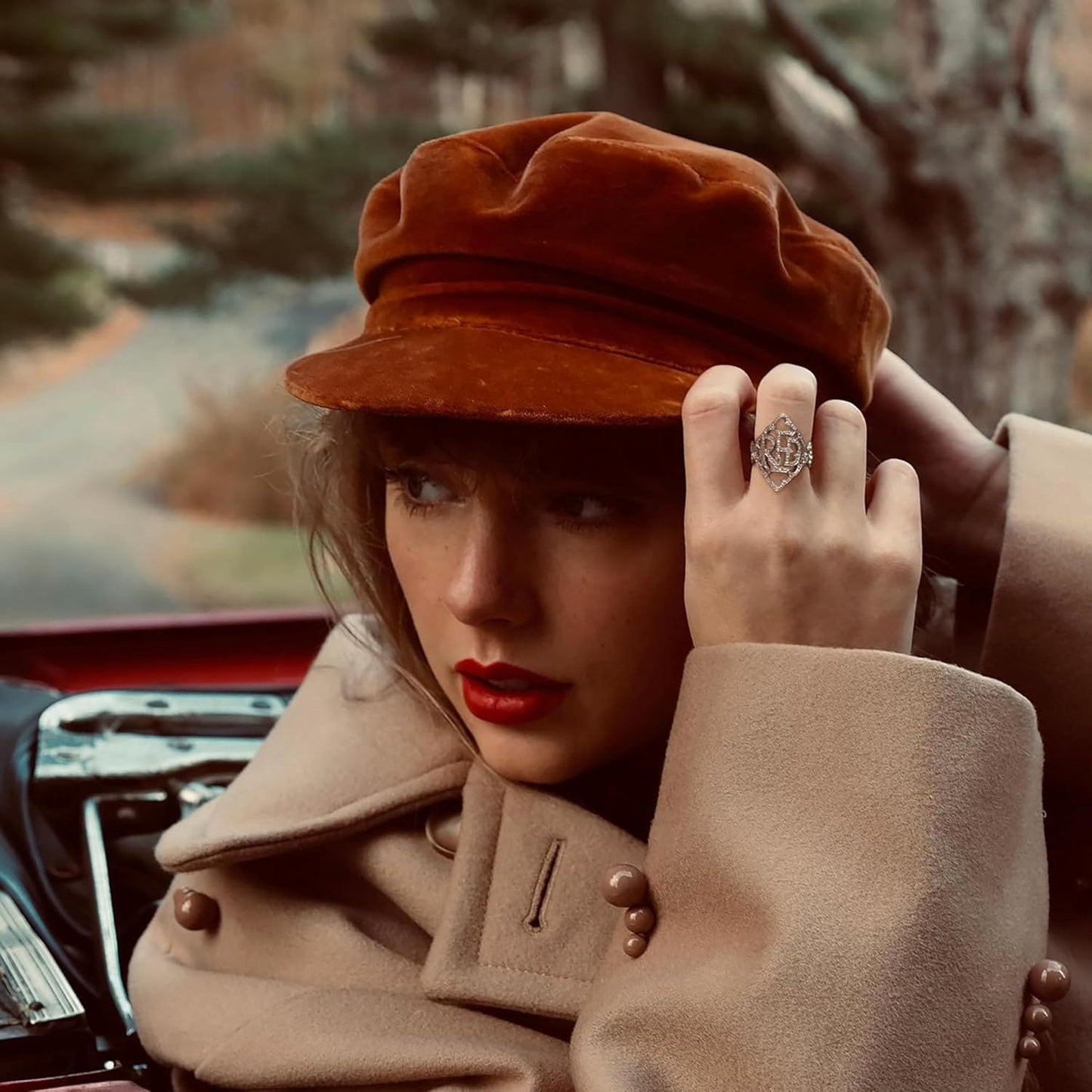 Woman wearing a brown hat and coat with a blurred outdoor background