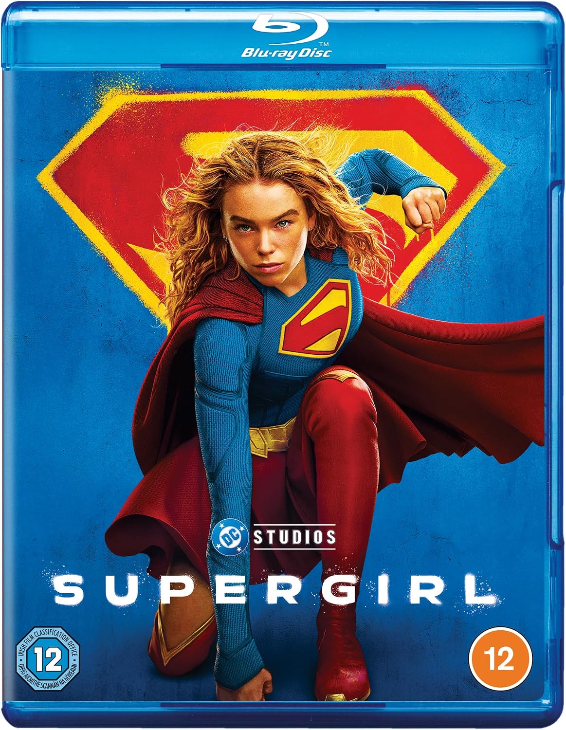 Blu-ray cover for the movie Supergirl, featuring a blue background with the character Supergirl in a red and blue costume, a large red and yellow S-shield behind her, and the Blu-ray Disc and DC Studios logos.