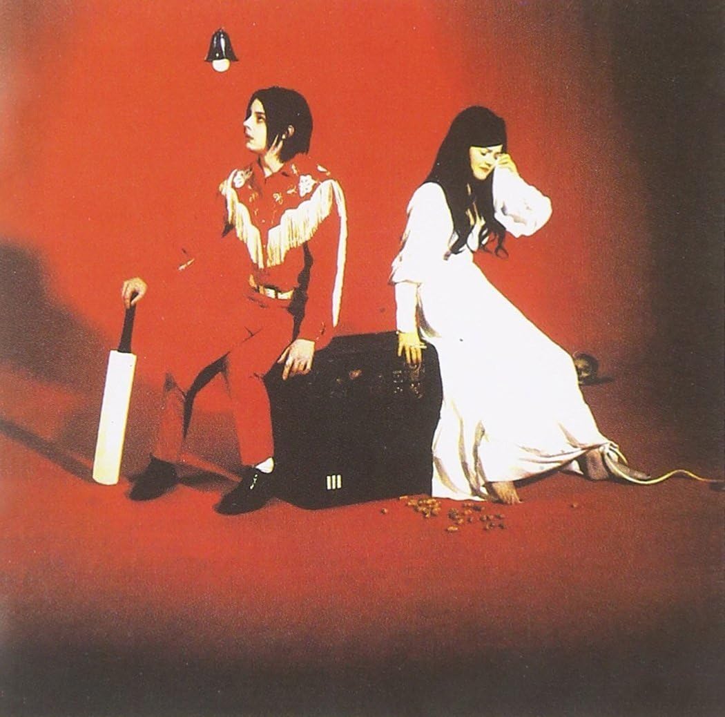 Two people sitting on a red background with a suitcase and umbrella.