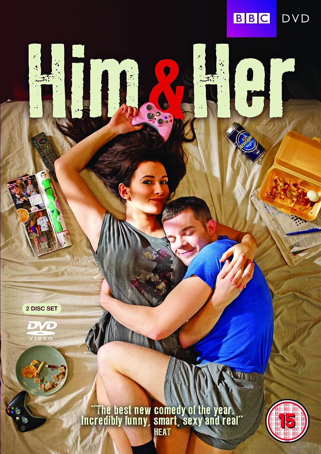 The cover image shows the DVD cover for 'Him & Her - Series 1'. It features two people, a man and a woman, sitting closely together on a bed, with various items such as a pizza, a remote control, and a book around them, suggesting a casual, relaxed setting.