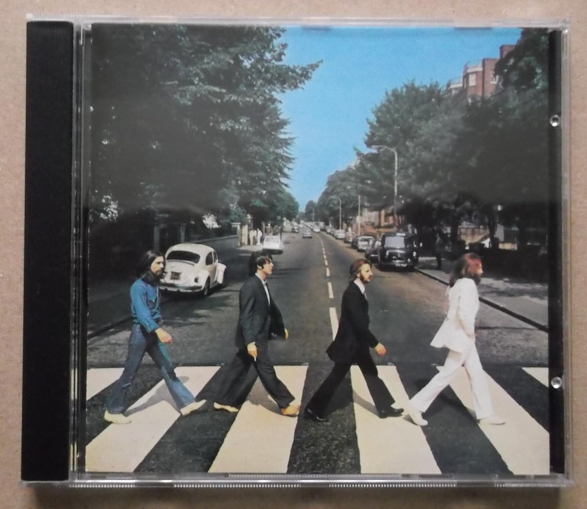 A square CD case showing the iconic Abbey Road album cover artwork with the four band members walking across a zebra crossing on a tree-lined street.