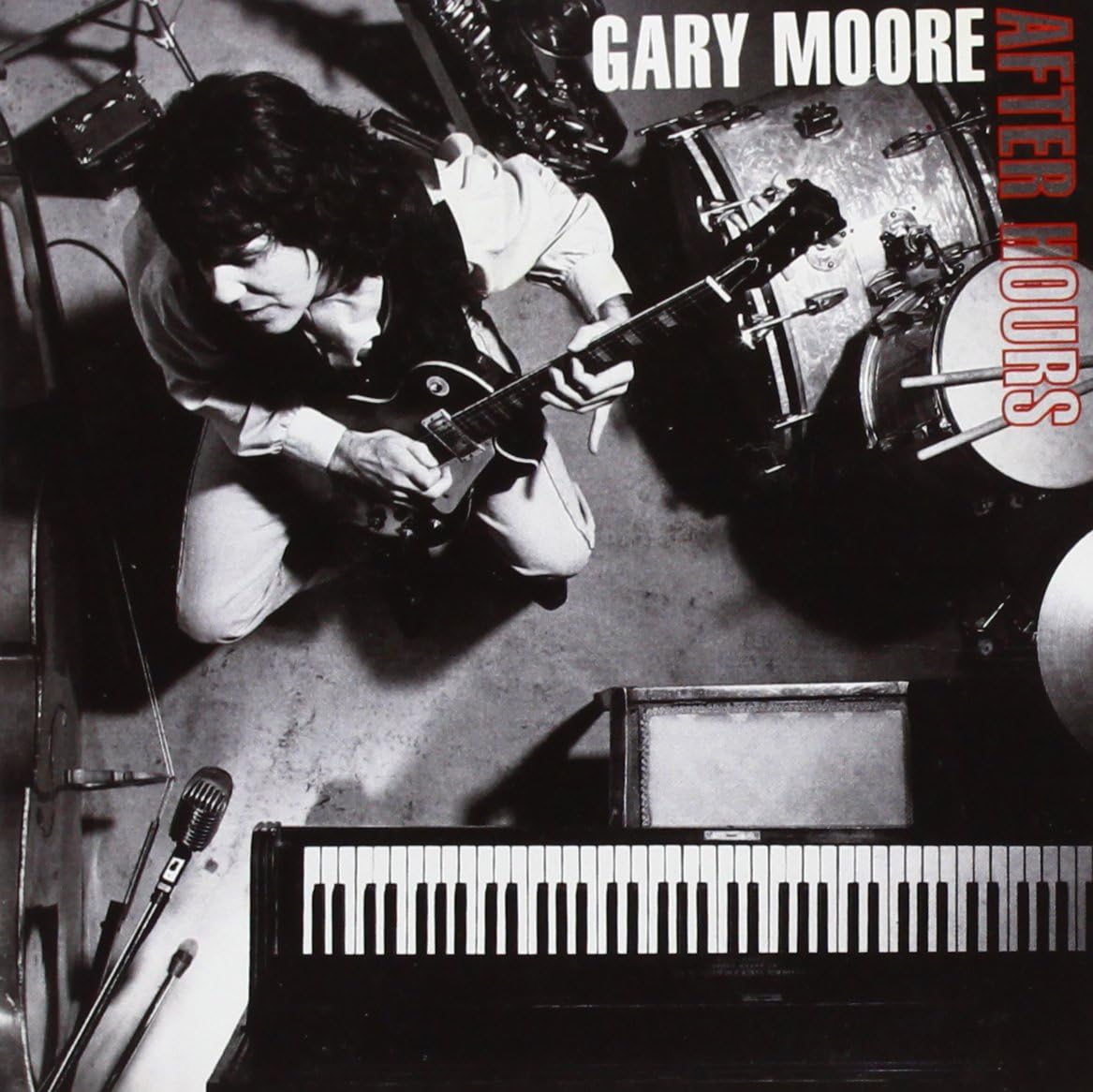 Album cover for Gary Moore's 'After Moors', featuring a black-and-white overhead photograph of the musician playing an electric guitar in a studio setting with a keyboard, drums, and microphones visible. The text 'GARY MOORE' appears at the top and 'AFTER MOORS' vertically on the right.