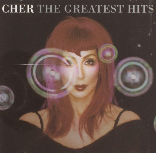 Album cover for 'Cher The Greatest Hits' with a stylized portrait of Cher and abstract designs.