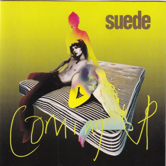 Album cover for 'Coming Up' by Suede featuring a person on a striped couch with colorful abstract elements.