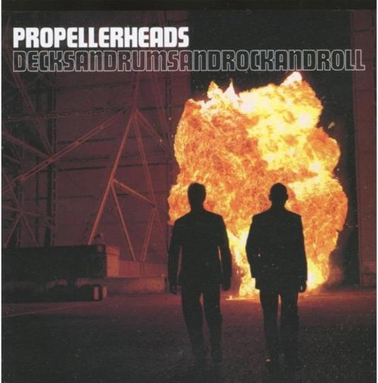 Album cover for 'Decks and Rums and Sandrock and Roll' by Propellerheads, featuring two silhouetted figures facing a massive orange and yellow explosion in a dark industrial setting.