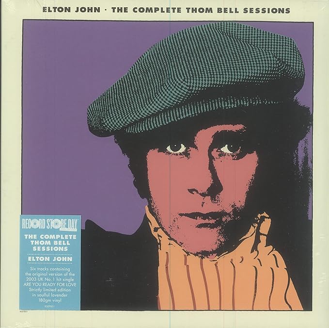 Elton John album cover for 'The Complete Thom Bell Sessions' featuring a black and white image of Elton John with a hat and mustache, set against a purple background.