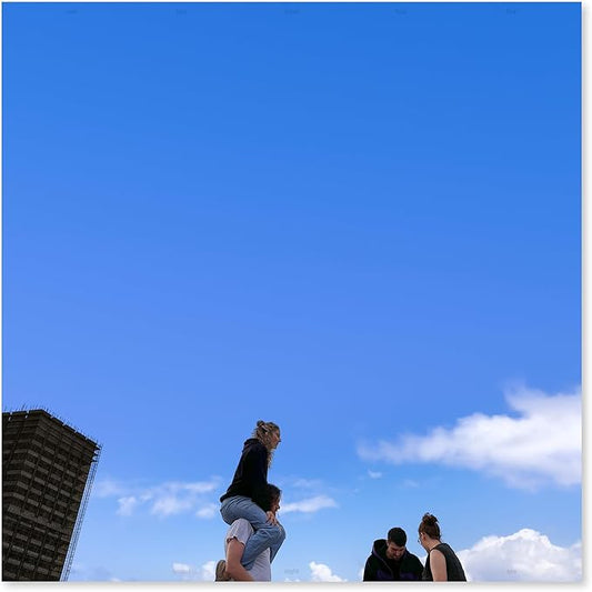 Three people standing on a ledge with a clear blue sky and a building in the background