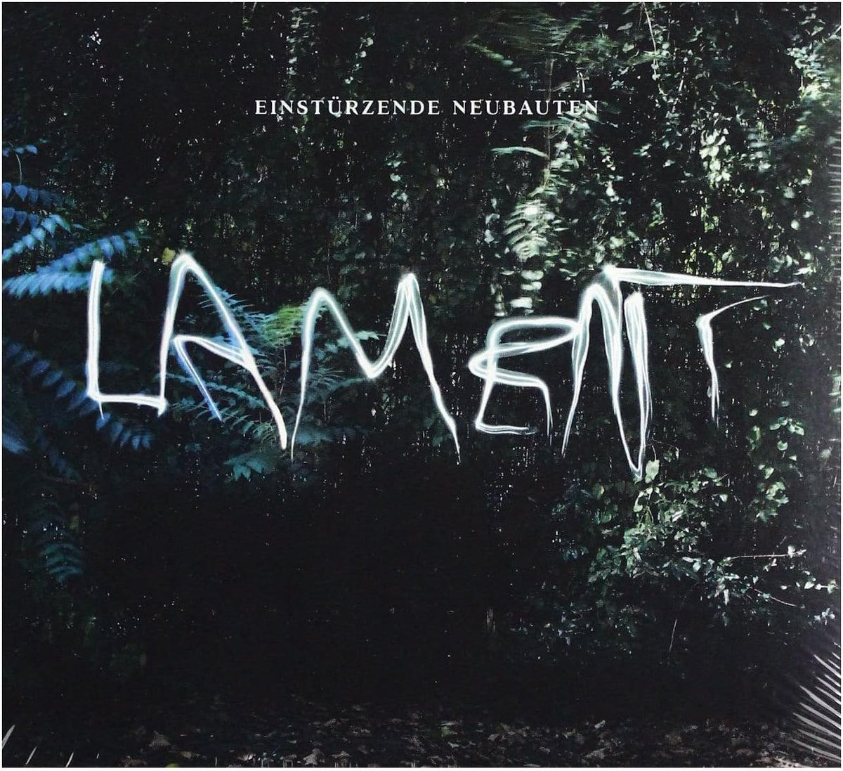 Album cover for Einstürzende Neubauten's 'Lament', featuring white graffiti-style text spelling 'LAMENT' over a dark, misty forest background.