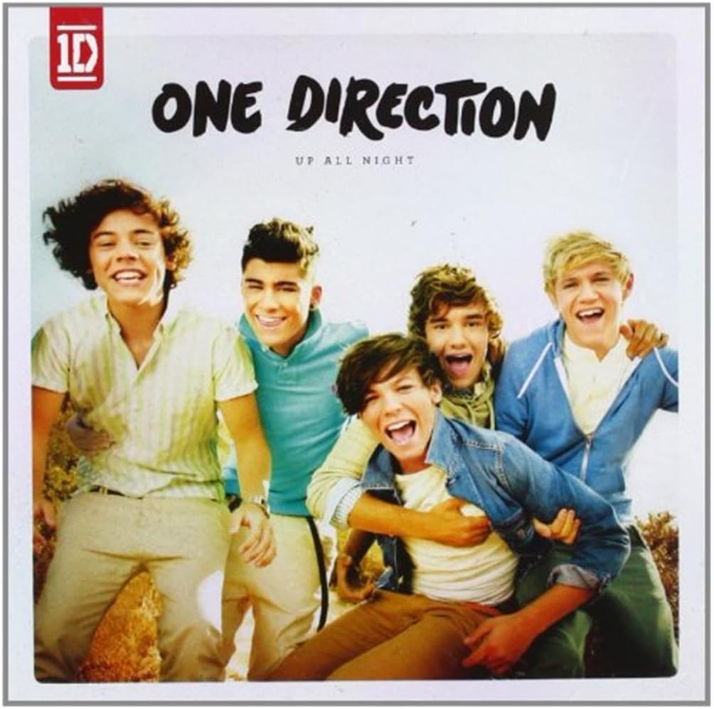 Album cover of One Direction with four members posing outdoors, featuring the band's logo.