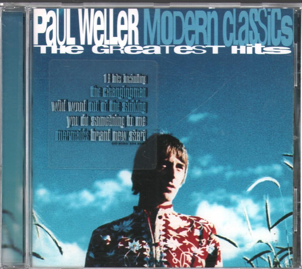 CD cover of Paul Weller Modern Classics: The Greatest Hits featuring a portrait of the artist against a blue sky background with text and branding.