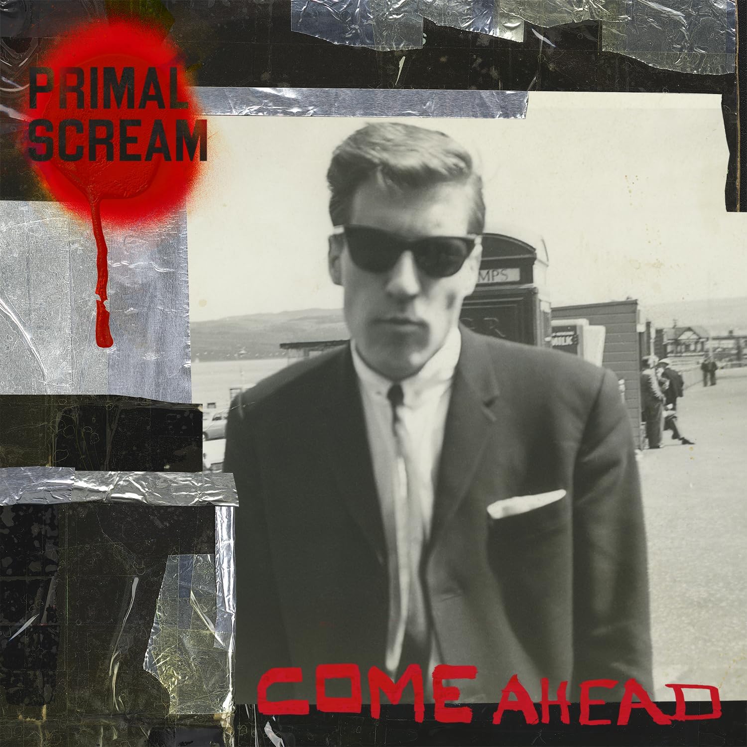 The image shows the cover of the Primal Scream album 'Come Ahead' on black vinyl. It features a black and white photo of a man with sunglasses and a suit, with the band name and album title text in red and white.