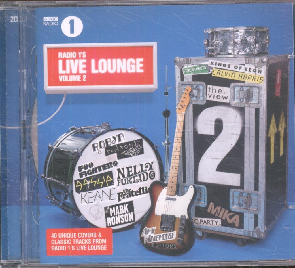 CD cover for BBC Radio 1 Live Lounge Volume 2, featuring a blue background with a red title box, a drum set, an electric guitar, and a large black equipment case with stage-like labels.