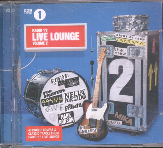 CD cover for BBC Radio 1 Live Lounge Volume 2, featuring a blue background with a red title box, a drum set, an electric guitar, and a large black equipment case with stage-like labels.