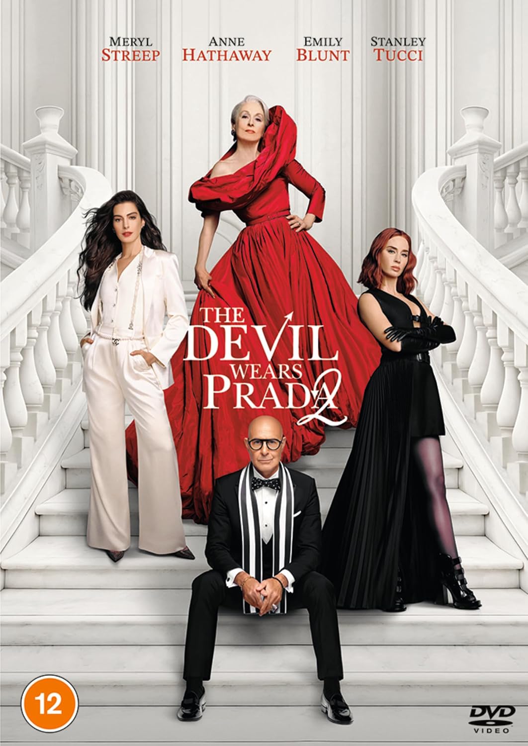 The Devil Wears Prada 2 DVD movie cover featuring Meryl Streep, Anne Hathaway, Emily Blunt, and Stanley Tucci posing on white stairs. Meryl Streep is in a large red gown, Anne Hathaway is in a white pantsuit, Emily Blunt is in a black dress, and Stanley Tucci is seated in a black tuxedo.