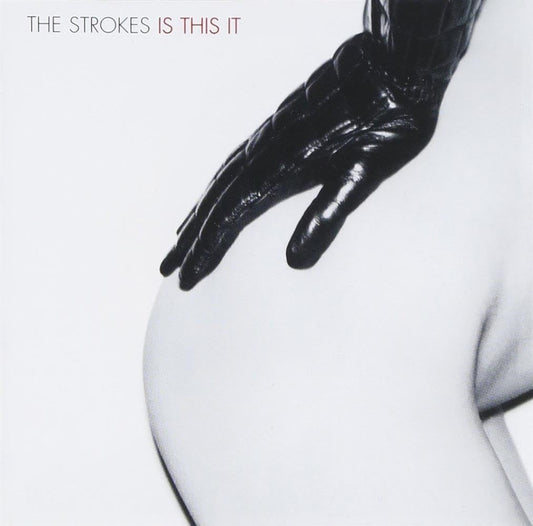 Album cover with a black-gloved hand on a white surface, featuring 'The Strokes' and 'Is This It' text.