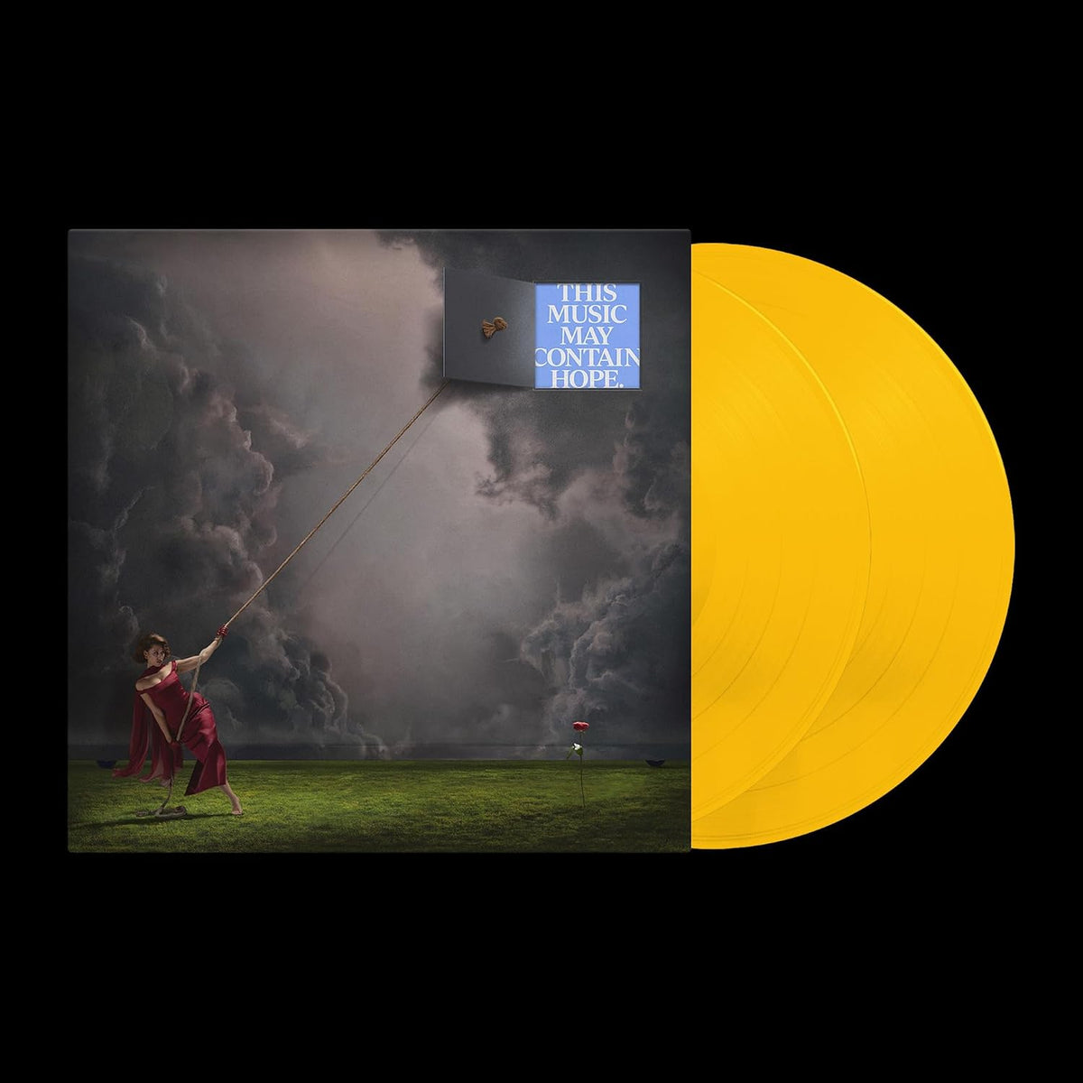 Vinyl record album cover with a surreal scene of a woman flying a large black kite over a grassy field under stormy clouds, alongside a bright yellow vinyl disc on a black background.