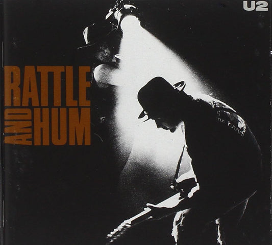 Album cover for U2's 'Rattle and Hum' with silhouettes of musicians under a spotlight.