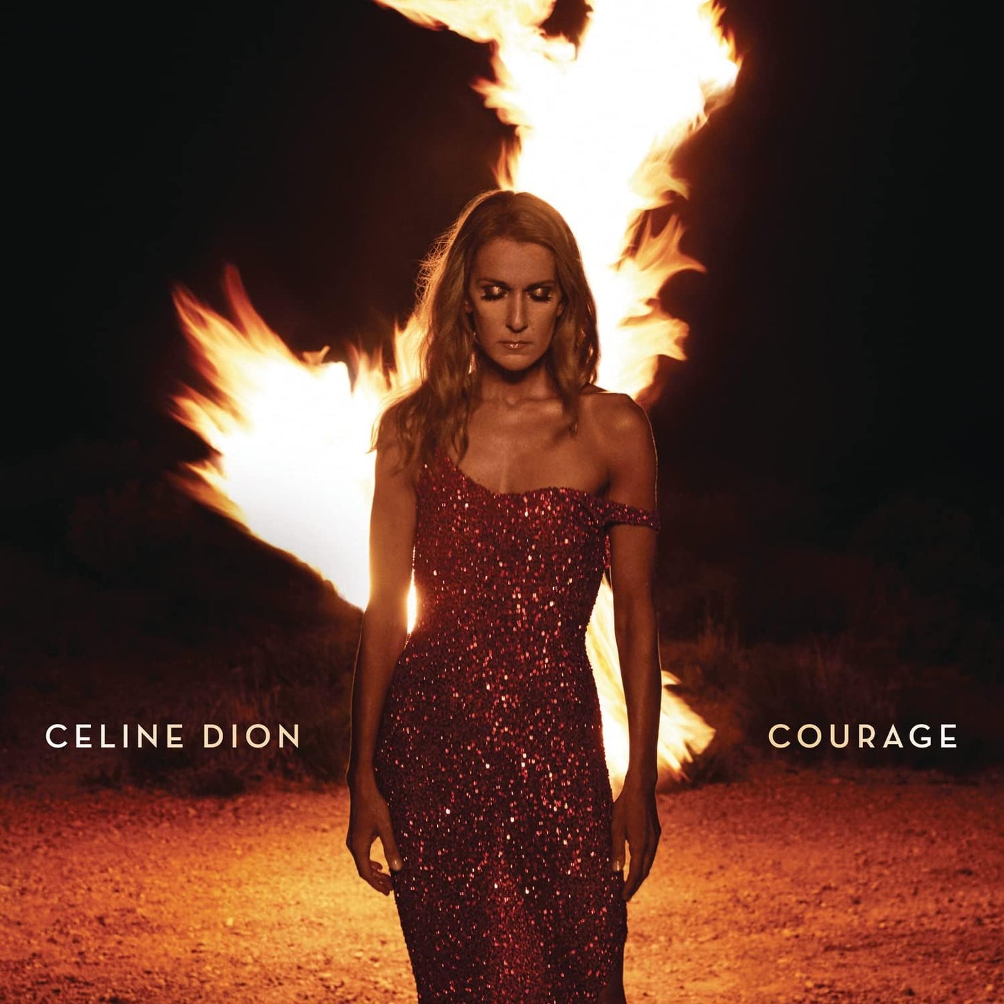 Céline Dion standing in front of a fiery backdrop with 'COURAGE' text overlay, wearing a red dress and a sparkling jacket.