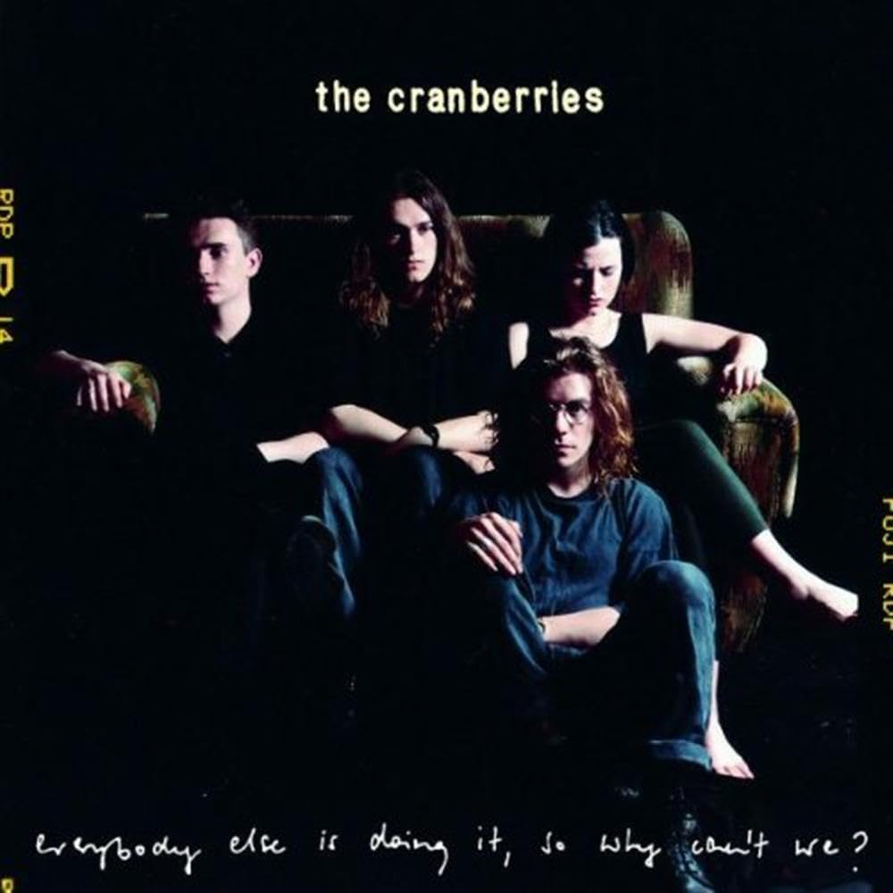 The Cranberries album cover for 'Everybody Else Is Doing It, So Why Can't We?', showing the band members seated in a dark room with the band's name at the top and the album title at the bottom.