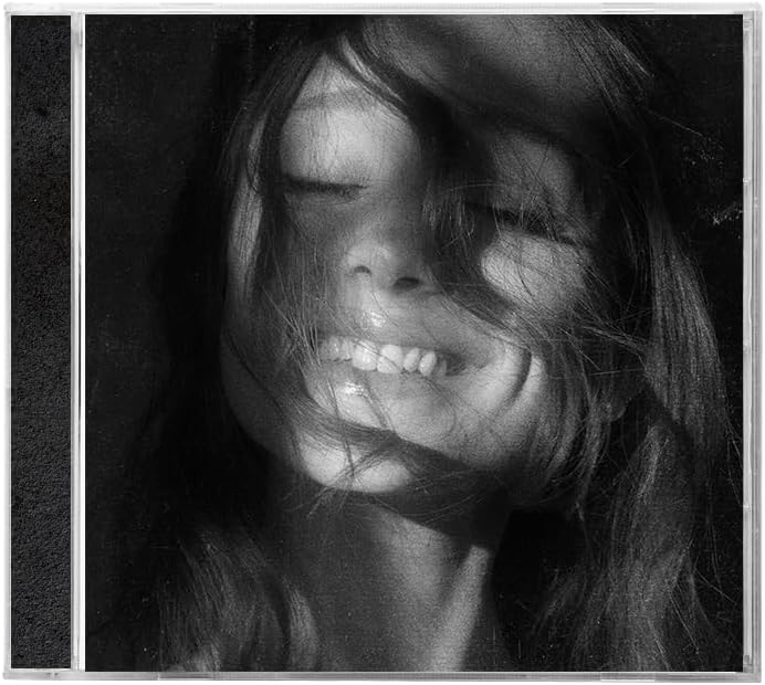 Black and white close-up portrait of a woman with closed eyes and messy hair, framed with a thin white border and a narrow dark strip on the left.