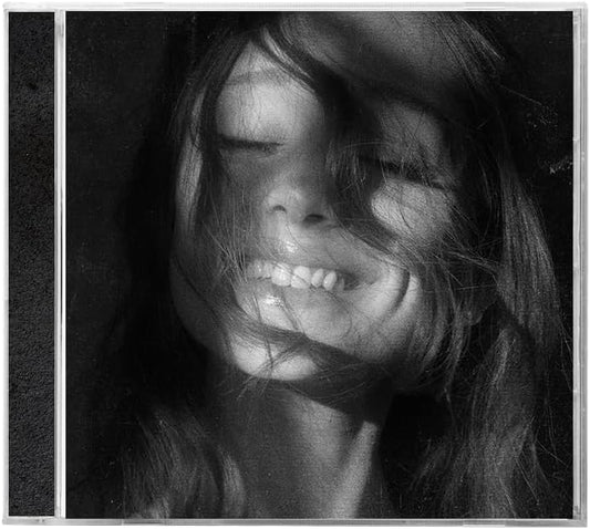 Black and white close-up portrait of a woman with closed eyes and messy hair, framed with a thin white border and a narrow dark strip on the left.