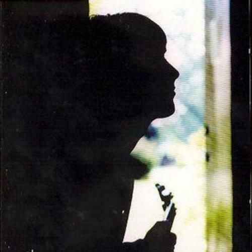 A black and white image of a person holding a guitar, with a blurred background.
