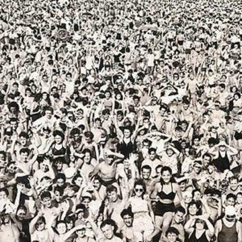 Black and white photo of a crowd at a George Michael concert, with people raising their arms and singing along.